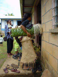 Deze vrouw in Tonga klederdracht kijkt naar binnen naar de optredens van het Peace Corps